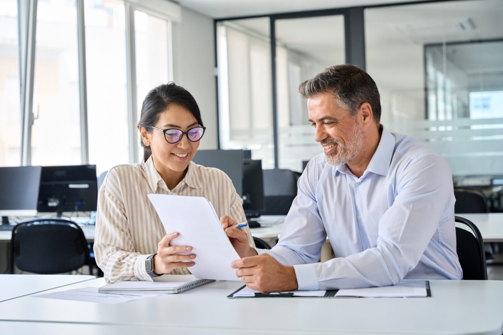 Two colleagues discussing documents in a modern office.