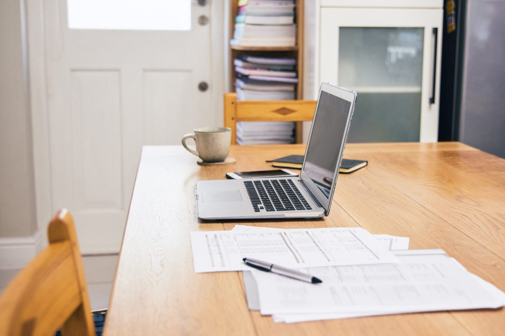 Laptop and documents on a wooden table in a home office.