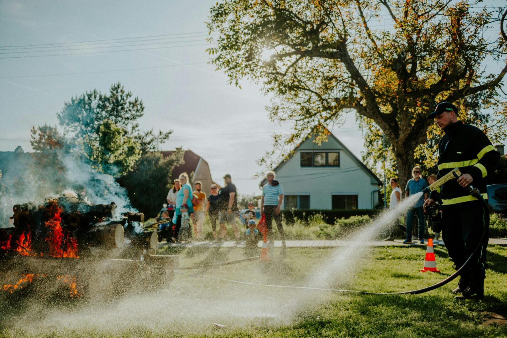 Children playing outside in a sunny backyard with water sprinklers.