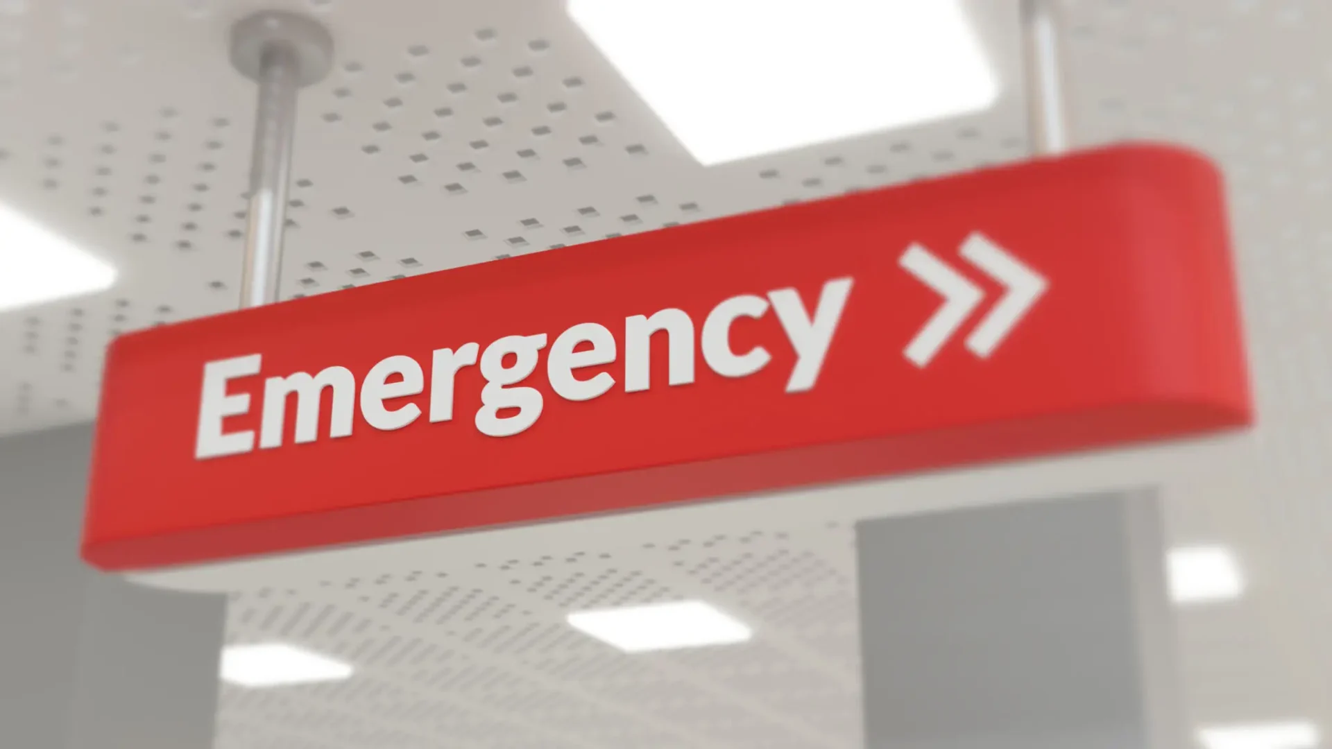 Red emergency sign with white text and arrows indoors.