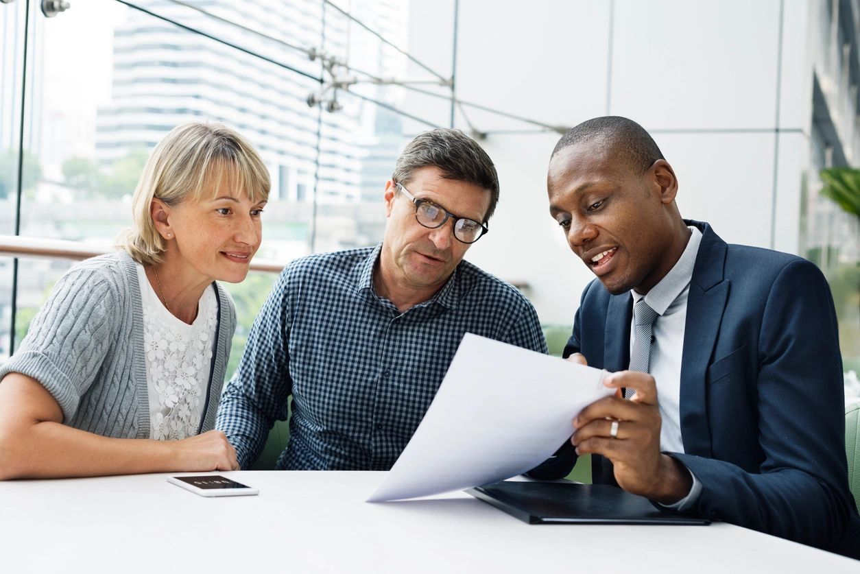 Three professionals discussing a document in a bright office.