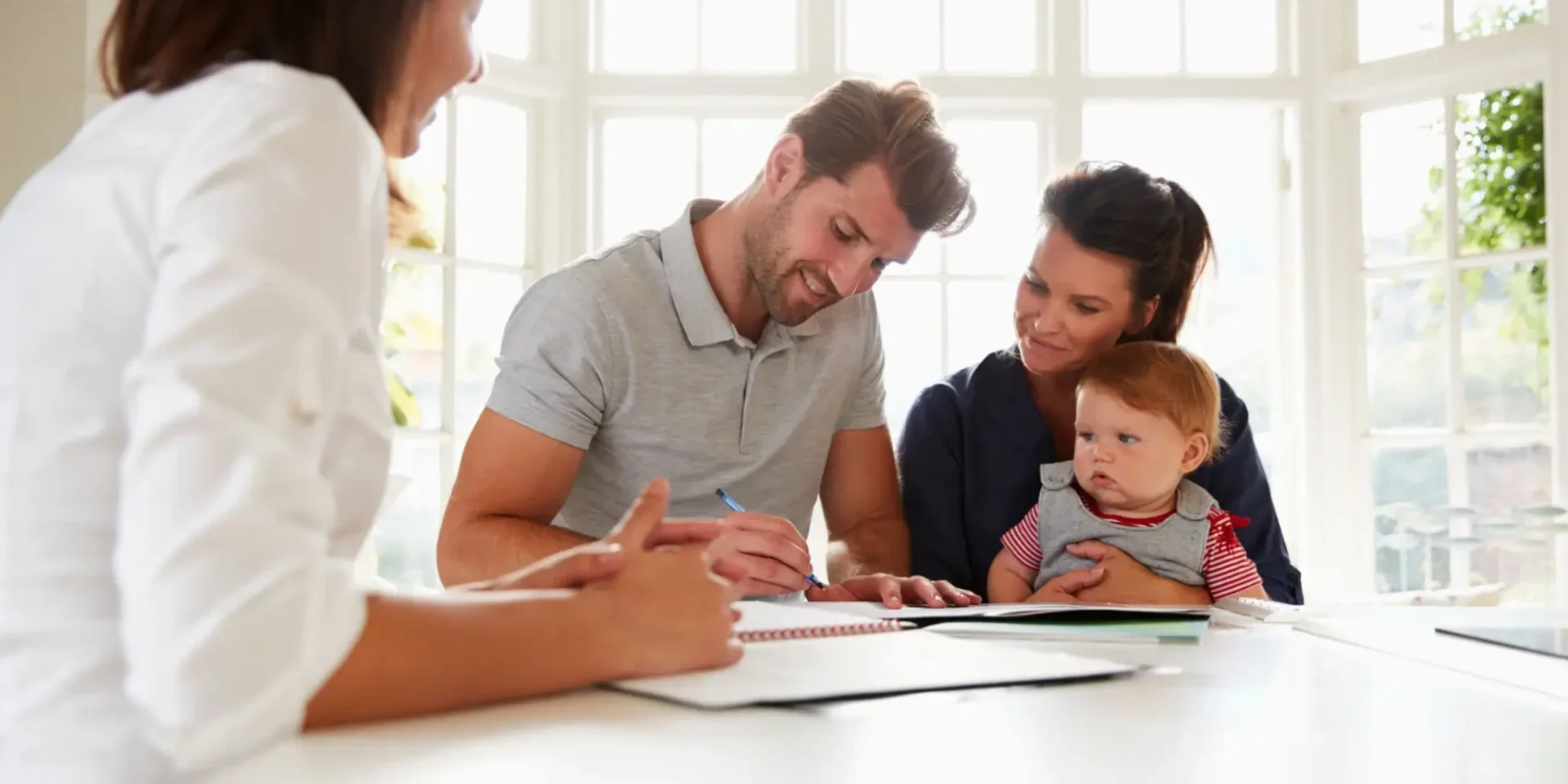 Family signing documents with a professional at a table.